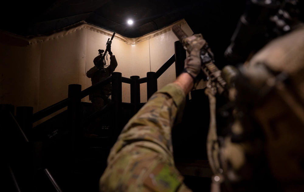Two operators working a stairwell with weapons angled upward