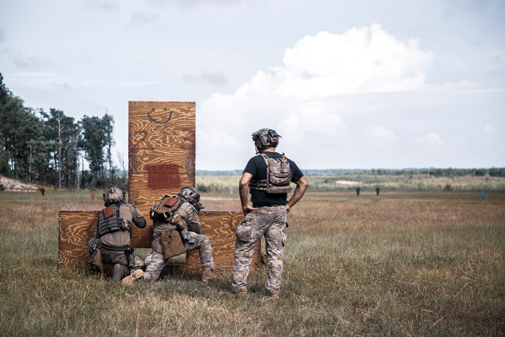 Service members training behind wooden cover at an outdoor range