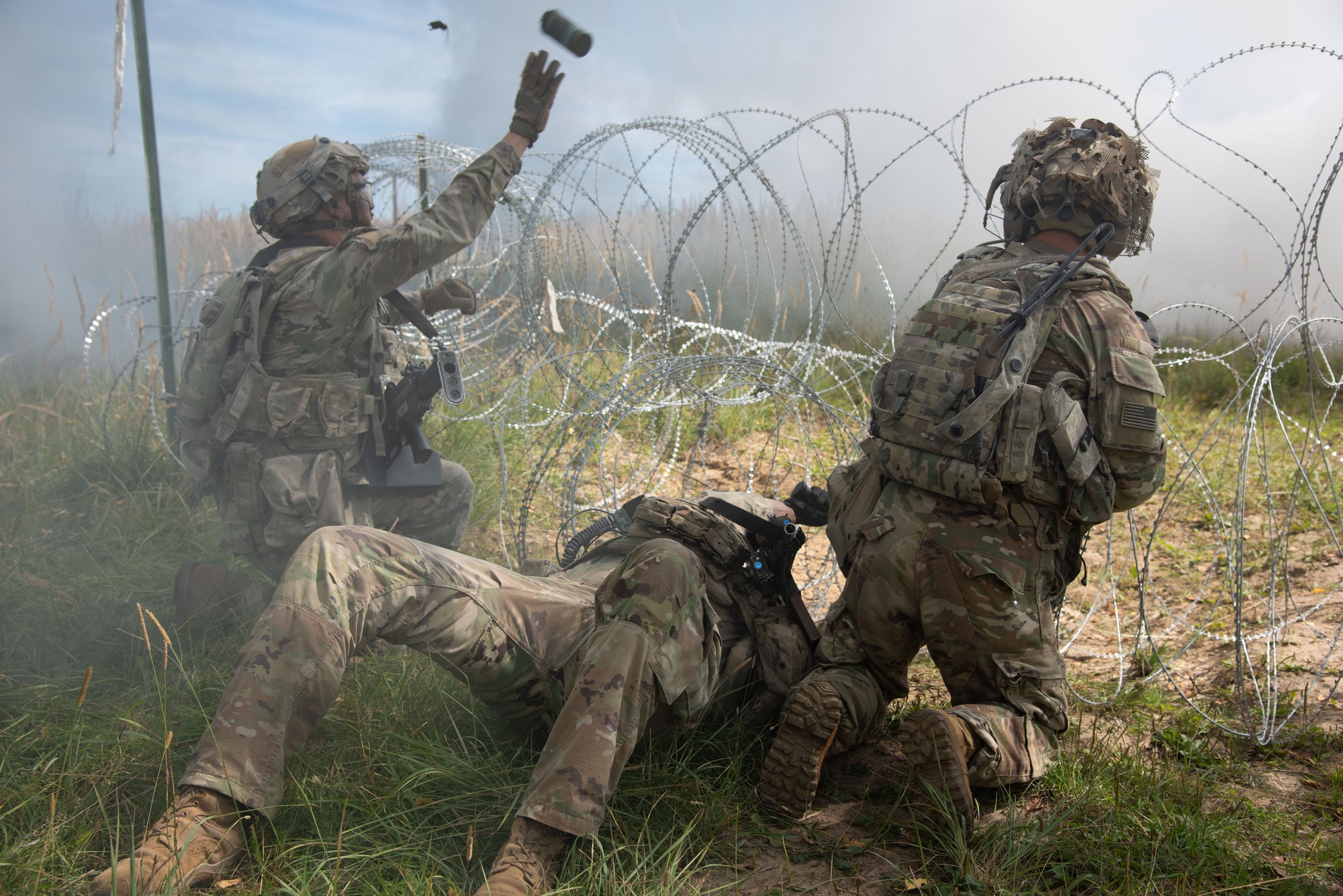Team moving through wire and smoke obscuration